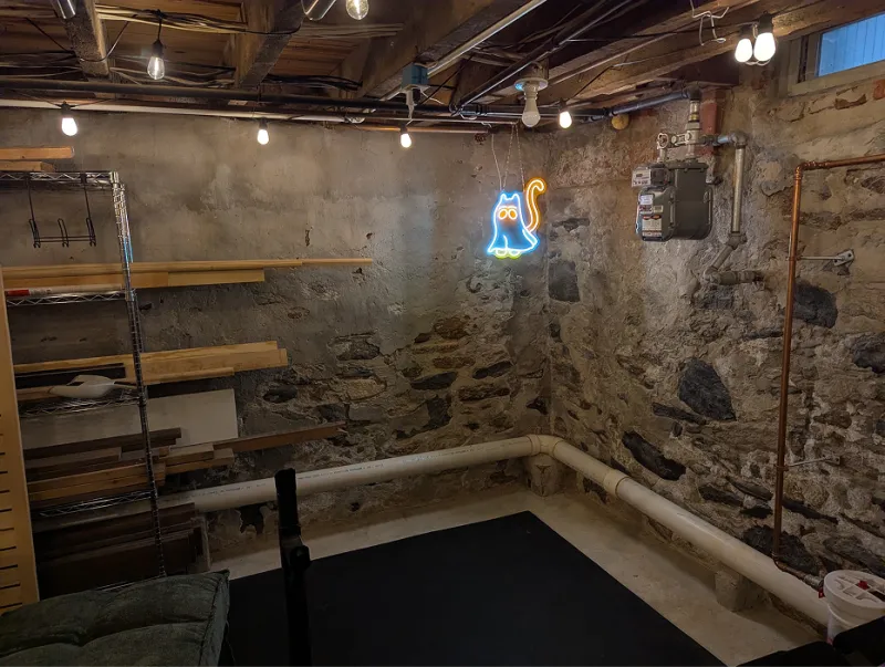 Cleared basement corner with stone walls, string lights, and a dark floor mat